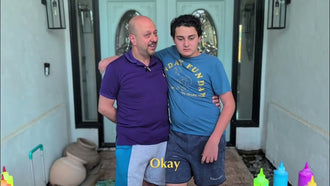 A man and a teenage boy with their arms around each other outside a front door