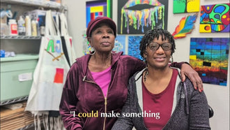 Two women smiling in front of colorful abstract paintings in the Blissful Seeds art studio