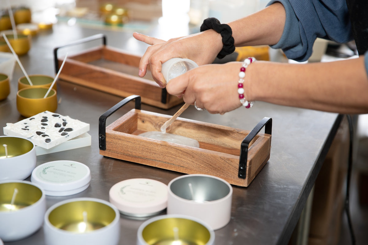 Hands finishing handmade candles and a resin tray in the Blissful Seeds workshop