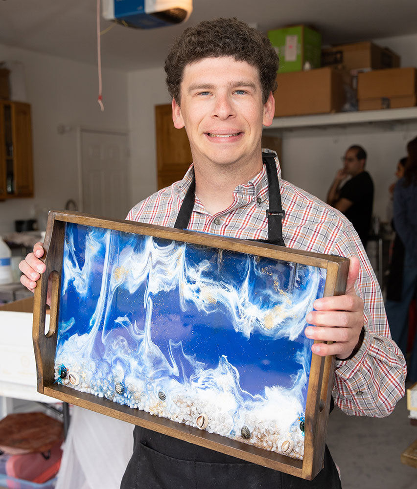Blissful Seeds artist Nick holding his blue ocean wave resin tray
